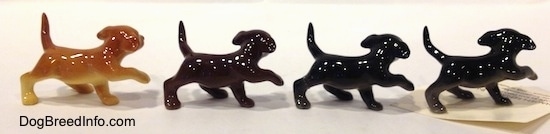 The right side of four Labrador Retriever puppy figurines in different color variations with there paws in the air. 
