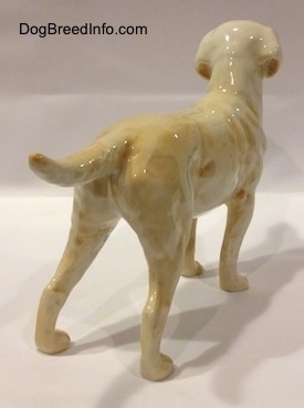 The back right side of a yellow Labrador Retriever. The tail of the figurine is medium length and sticking up.