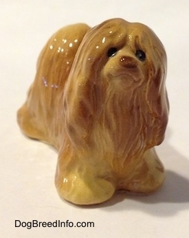 A brown figurine of a Lhasa Apso that has black circles for eyes.