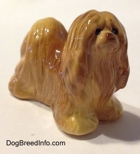 The front right side of a brown Lhasa Apso figurine. The figurine is looking up and to the right.