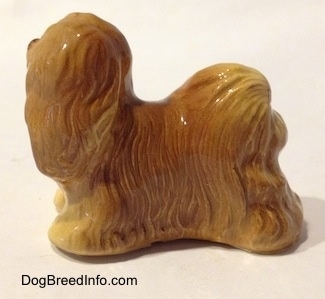 The left side of a brown figurine of a Lhasa Apso figurine. The figurine has fine hair details.