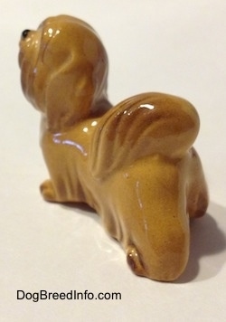 The back left side of a Lhasa Apso figurine. The figurine has short legs.