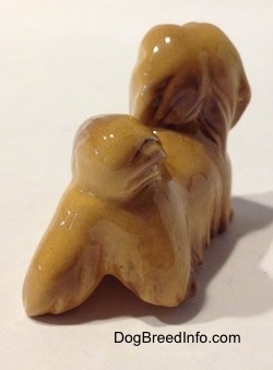 The back right side of a Lhasa Apso figurine. It is hard to differentiate the ears of the figurine from its head.