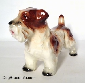 The front left side of a figurine of a white with brown Lucas Terrier. The figurine has ears that are hard to differentiate from its body.