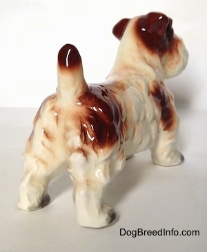 The back right side of a figurine of a white with brown Lucas Terrier. The figurine has ruffled hair along its side.
