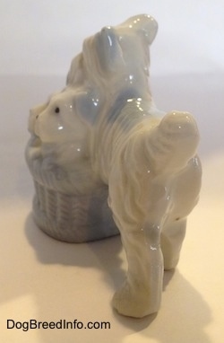 The right side of a figurine of a bone china Miniature Schnauzer standing next to her basket of puppies. The tail of the figurine has its fluffy tail arched in the air.