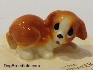An orange and white puppy figurine that has big sad eyes.