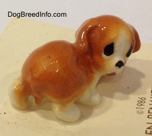 The back right side of an orange and white puppy figurine. The figurine has its tail in between its legs.