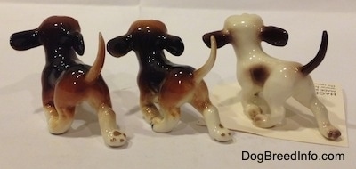 The back left side of three figurines of running dogs in different color variations. The figurines are glossy.