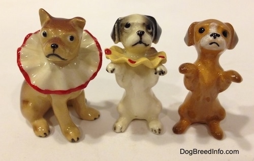 Three circus dog figurines and two of them are in a begging pose.