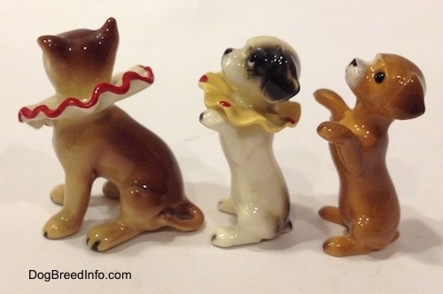 The left side of three figurines of circus dogs. The right most figurines have short tails and the forward most figurine has a medium length tail.