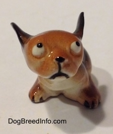 A running puppy miniature figurine. The figurines ear are up as they are flying back.