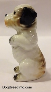 The left side of a bone china white with black Peek-A-Poo in a begging pose figurine. The figurine is wrinkled and glossy.