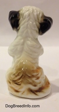The back of a bone china white with black Peek-A-Poo in a begging pose figurine. The figurine has fine hair details.