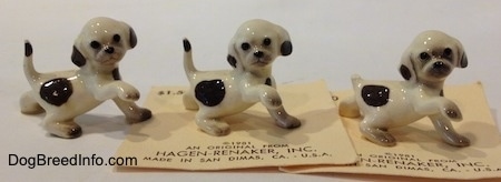 The right side of three white with brown Hound dog figurines. All the figurines have black circles for eyes.