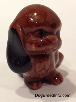 The front right side of a brown with black mixed dog figurine that is in a sitting position. The ears of the figurine are black.