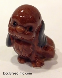 A brown with black mixed dog figurine in a sitting position.