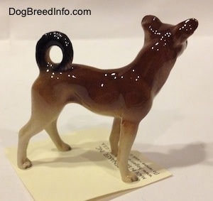 The right side of a figurine of a mixed breed dog figurine. The figurine is very glossy.