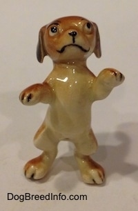 A figurine of a dog standing on its hind legs in a begging pose.