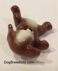A brown with white mixed breed dog figurine. The figurine is glossy.