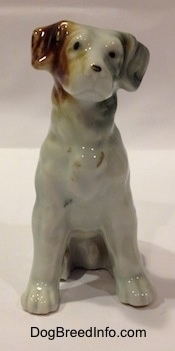 A bone china brown, white and black mixed breed dog in a sitting pose figurine.