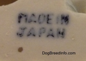 Close up - The underside of a bone china mixed breed dog figurine that has a stamp that reads 'Made In Japan'.