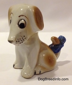 A brown and white mixed breed puppy figurine in a sitting pose.