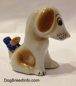 The right side of a figurine of a brown and white mixed breed puppy. The puppy has a blue bow attached to its tail.