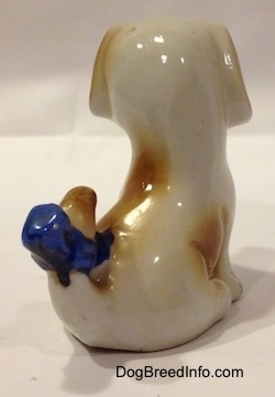 The back right side of a brown and white figurine of a mixed breed puppy. The figurine is very glossy.