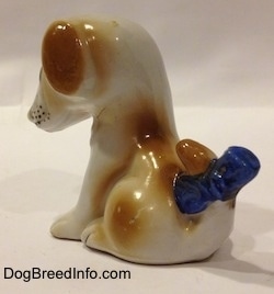 The back left side of a figurine of a brown and white mixed breed puppy. The ears of the figurine are attached to its head.
