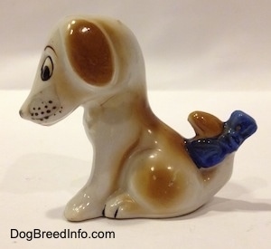 The left side of a brown and white mixed breed puppy figurine. The figurine has dots around its muzzle.
