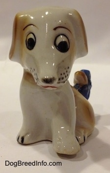 A figurine of a brown and white mixed breed puppy figurine. The figurines eyes are slightly off.