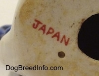 Close up - On the underside of a figurine of a mixed breed dog is a red 'JAPAN' stamp.