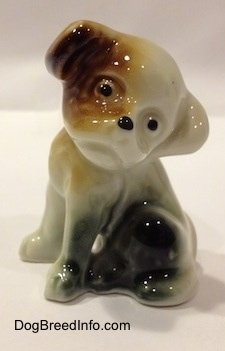 A brown, black and white dog figurine that is in a sitting pose.