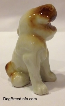 The front right side of a brown, black and white dog sitting figurine. The figurines ears are attached to the 