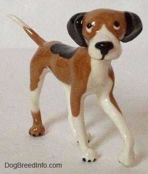 The front right side of a tri-color Papa Dog figurine. The figurine has long and skinny legs.