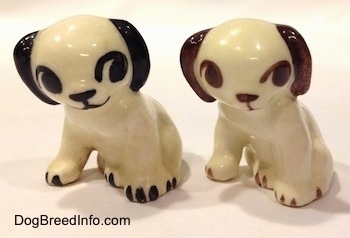 Two figurines of a dog in a sitting position. The figurines are different color variations.