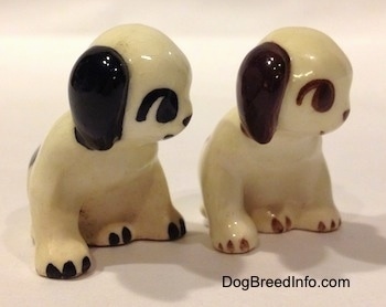 Two dog figurines that are in a sitting position. They have big circles for eyes.