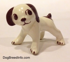 A white with brown dog standing figurine. The figurine has colored parts.