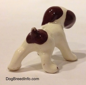 The back of a white with brown dog standing figurine.