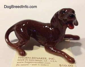 The right side of a brown playful dog figurine. The figurine has an open mouth.
