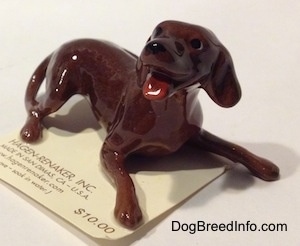 The front right side of a figurine of a brown playful dog. The figurine has long legs.