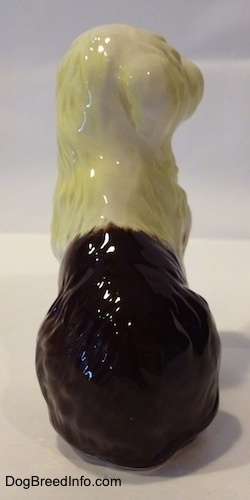 The back of a brown with white figurine of a porcelain Old English Sheepdog. The ears of the figurine are hard to differentiate from head.