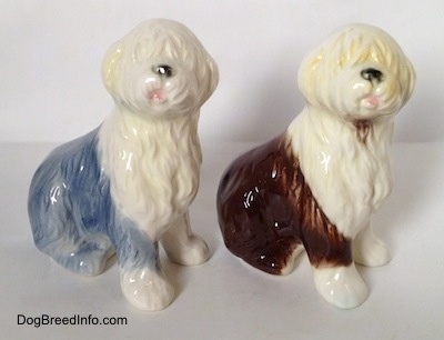 Two porcelain Old English Sheepdog figurines that are in a sitting positions. The figurines both have there mouths open.