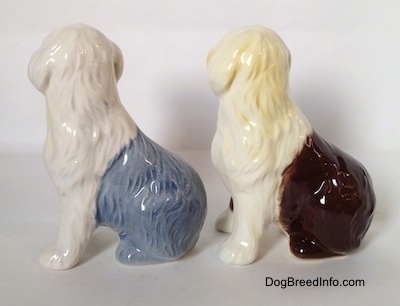 The left side view of two porcelain figurines of Old English Sheepdogs that are in a seated position. The figurines do not have tails.