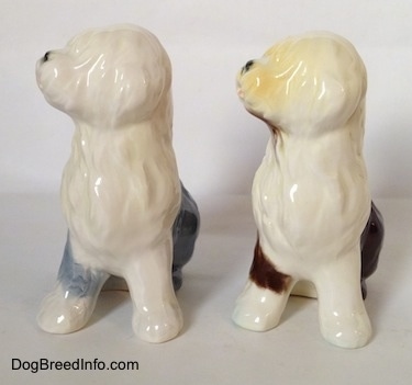 Two color variations of a porcelain Old English Sheepdog figurine that are in a seated position.