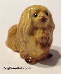 The front right side of a figurine of a tan Pekingese. The figurine has fine hair details.