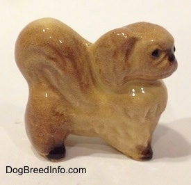 The right side of a tan with brown figurine of a Pekingese. The figurine has black paws.