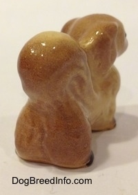 The back right side of a figurine of a tan with brown Pekingese. The tail of the figurine is arched onto its back.