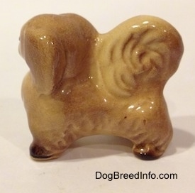 The left side of a figurine of a tan with brown Pekingese. The Pekingese has fine hair details.